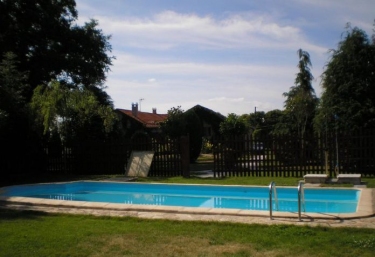 Acceso a la piscina rodeada de zonas verdes