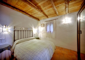 Habitación con cama de matrimonio y cabecero de forja en la casa rural