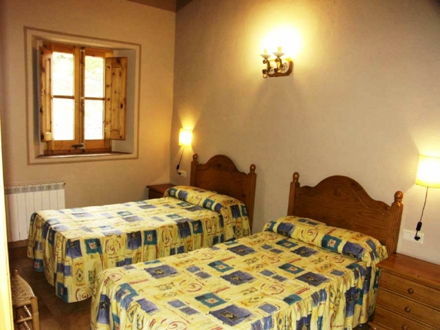 Dormitorio con dos camas individuales. Cabeceros y cajones de madera