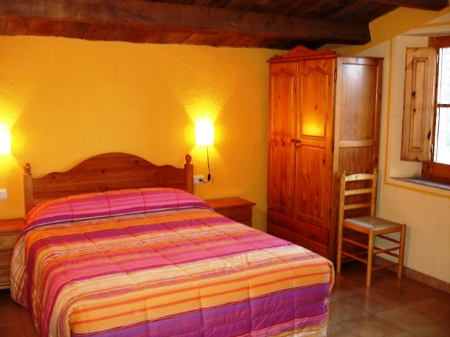 Dormitorio de matrimonio. Pared amarilla. Cabecero de madera