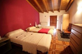 Dormitorio con tres camas y vigas al descubierto