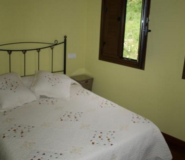 Dormitorio de matrimonio con colcha y ventanas de madera