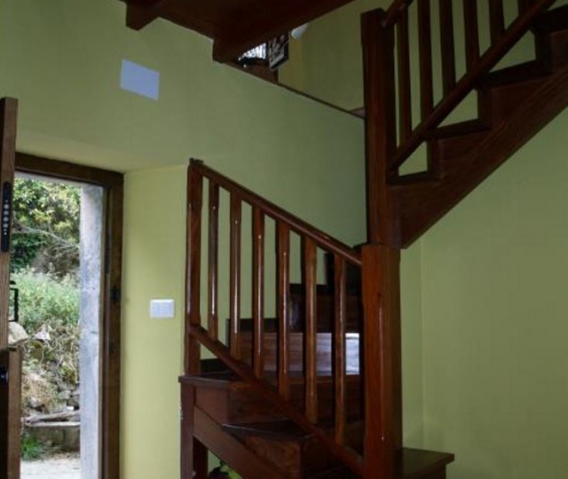 Entrada a la casa con escaleras de madera y puerta abierta