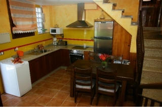 Cocina comedor con mesa de madera y escaleras