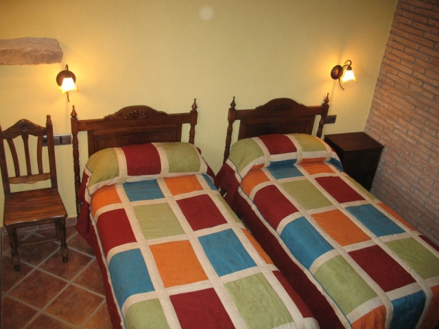 Camas individuales junto a pared de ladrillo visto