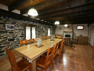 Salón con amplia mesa de roble y televisión de plasma de casa rural