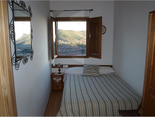 Dormitorio de la casa rural con espejo y ventanas