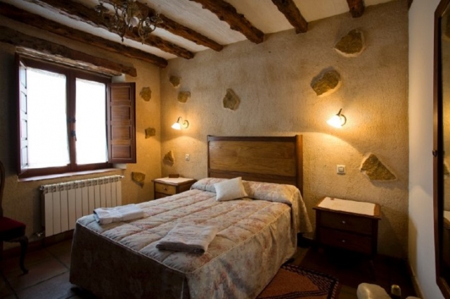 Dormitorio con cama doble y detalles de piedra en las paredes