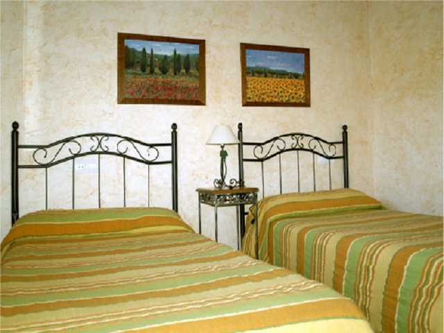 Dormitorio de camas individuales con cuadros de paisajes en la pared