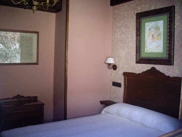 Dormitorio de matrimonio con cuadro sobre el cabecero de madera