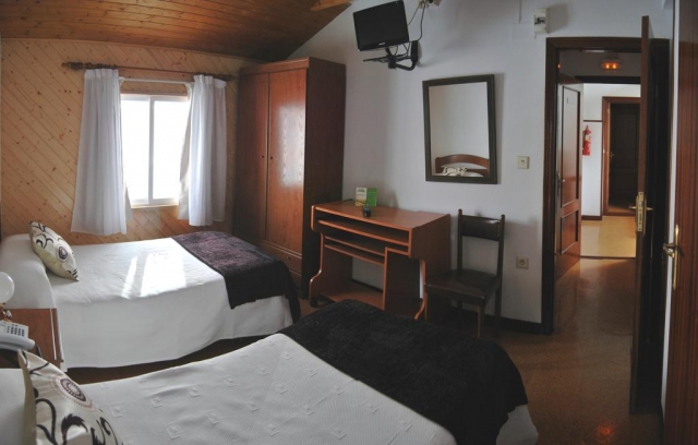 Dormitorio con un par de camas y tele de plasma