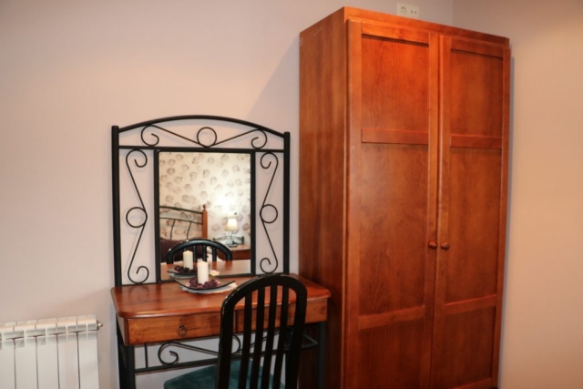 Dormitorio de matrimonio en marrones y mesa de madera delante