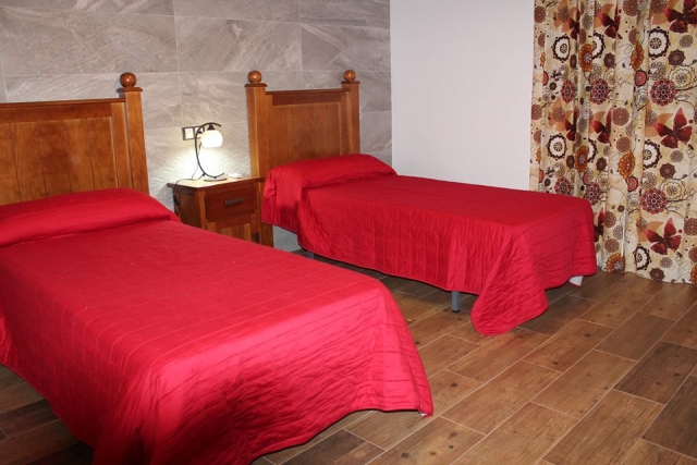 Dormitorio con un par de camas y suelo de madera