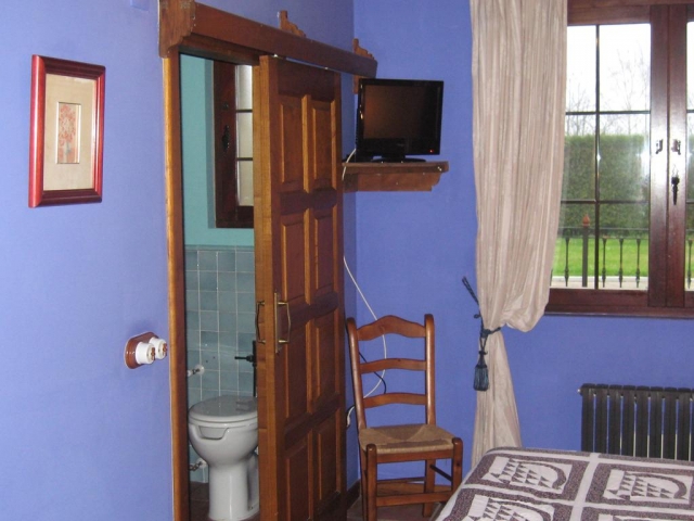 Dormitorio azul y su aseo con espejo delante