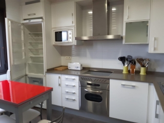 Cocina amplia de la casa con mesa auxiliar roja