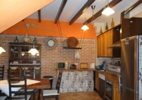 Mesa de comedor de la casa rural con la cocina al fondo