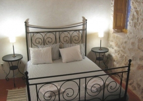 Dormitorio de matrimonio con forja y pared de piedra en la casa rural