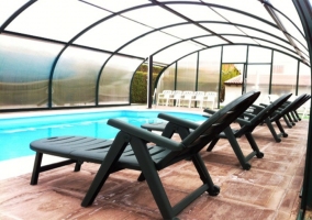 Piscina climatizada con hamacas