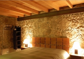 Dormitorio con un original diseño de madera en el cabecero y techo también de madera en la casa rural