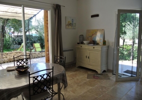  área de estar con sofá de cuero negro y mesa de café, cocina al fondo decorada en blanco y amoblado, mesa comedor con sillas al otro lado 