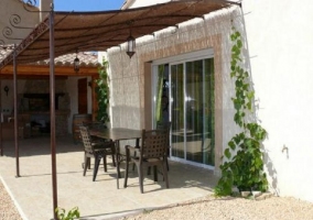  zona de terraza sombreada que da al salón y tiene mesa y sillas de comedor 