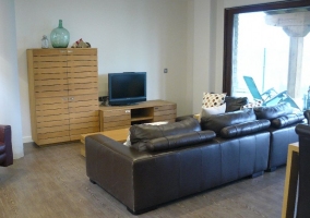 Salón con sillón negro y mueble con el televisor