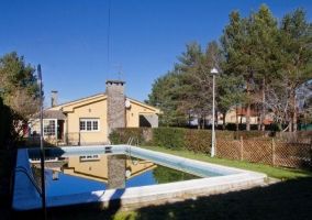 Vista exterior de la piscina y el alojamiento con chimenea