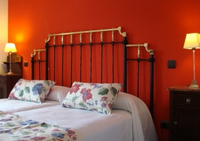 Dormitorio con pared roja y dos camas con estampado de flores