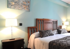 Dormitorio de paredes azules con dos camas compartiendo cabecero