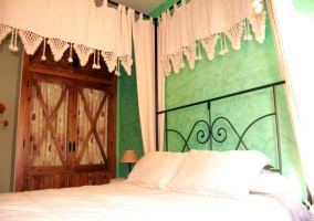 Dormitorio de matrimonio. Pared verde y dosel que cuelga