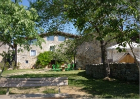 Vista de la fachada, jardín y pérgola de la casa rural