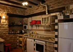 Cocina completa con paredes de piedra y horno