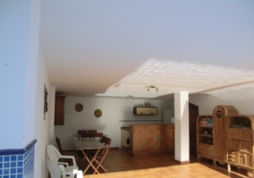 Zona techada con muebles de exterior, cocina y mueble junto a la piscina