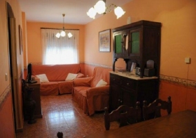 Sala de estar con dos sillones naranjas y televisor sobre mueble