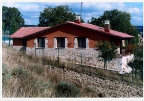 Vista desde atras de la casa rural con campo de labranza y valla que separa ambas partes