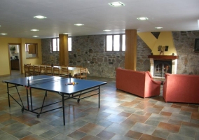 Sala de juegos con sofás y ping-pong y mesa de comedor