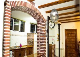 Vista de lavabo, armarios y frigorífico de la cocina desde el vestíbulo con el salón-comedor