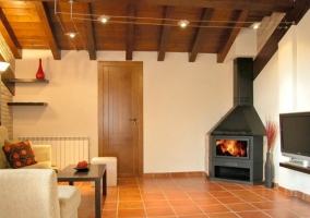 Zona de comedor y cocina de la casa rural con muebles de diseno rojo y chimenea de lena