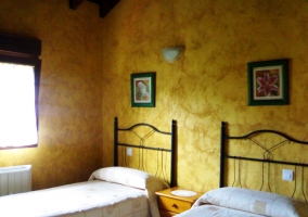 Dormitorio doble con dos camas y paredes amarillas