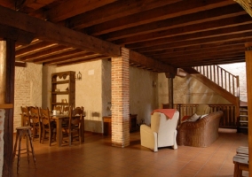 Sillones en sala de estar y mesas de comedor con cocina al fondo