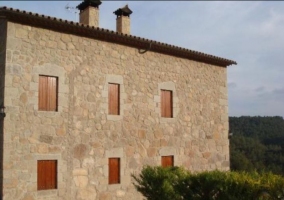 Acceso a la casa con fachada en piedra y naturaleza