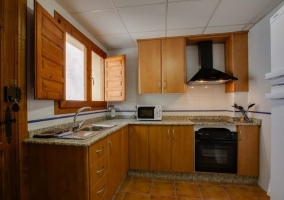 Cocina con muebles en madera y ventana en el centro