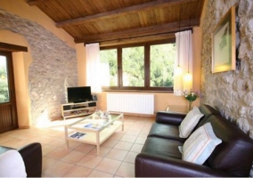 Sala de estar con paredes de piedra y sillones negros