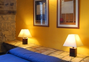 Dormitorio amarillo y con pared de piedra