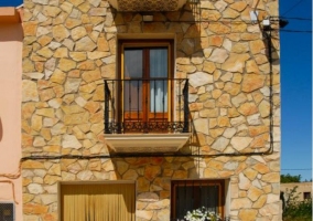 Acceso a la vivienda de tres plantas con fachada de piedra