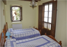 Dormitorio doble con dos camas y cabeceros de madera de la casa rural