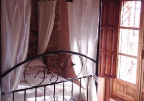 Dormitorio de matrimonio con dosel y telas