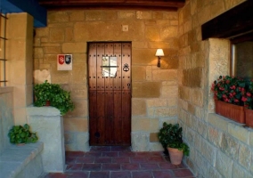 Entrada con puerta de madera y pared de piedra