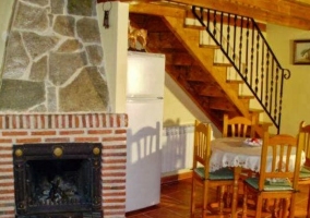 Sala de estar con mesa de madera y chimenea con piedra en la planta superior