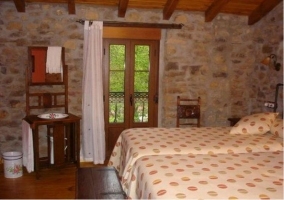 Dormitorio con dos camas y paredes de piedra de la casa rural